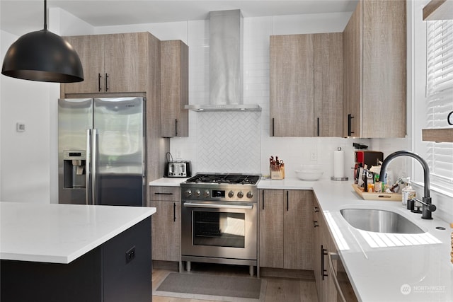 kitchen featuring sink, backsplash, hanging light fixtures, stainless steel appliances, and wall chimney exhaust hood