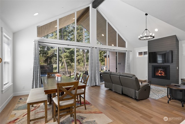 dining area with a notable chandelier, light hardwood / wood-style flooring, a large fireplace, and a healthy amount of sunlight