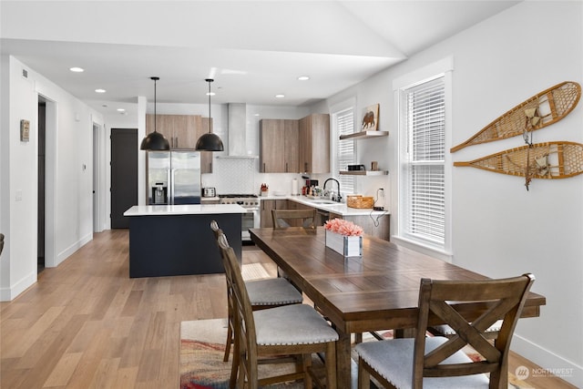 dining area featuring lofted ceiling, sink, and light hardwood / wood-style flooring