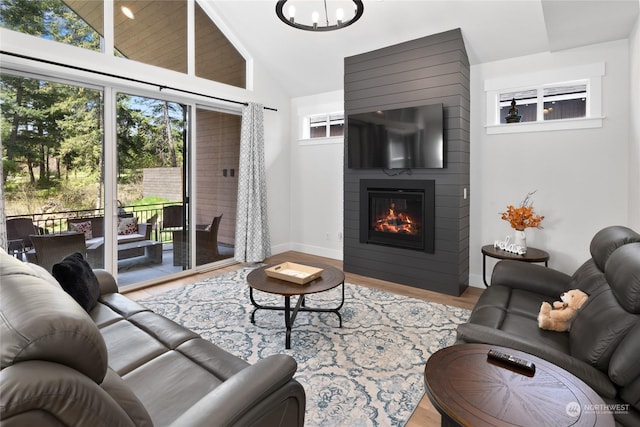 living room featuring a fireplace, high vaulted ceiling, a healthy amount of sunlight, and light wood-type flooring