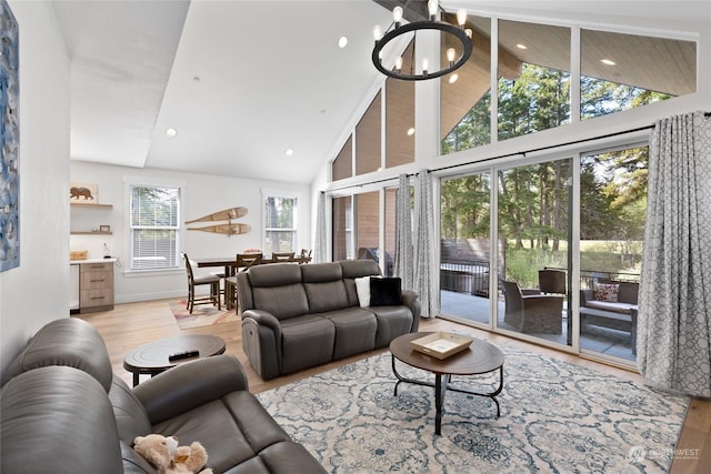 living room with high vaulted ceiling, light hardwood / wood-style floors, and a chandelier