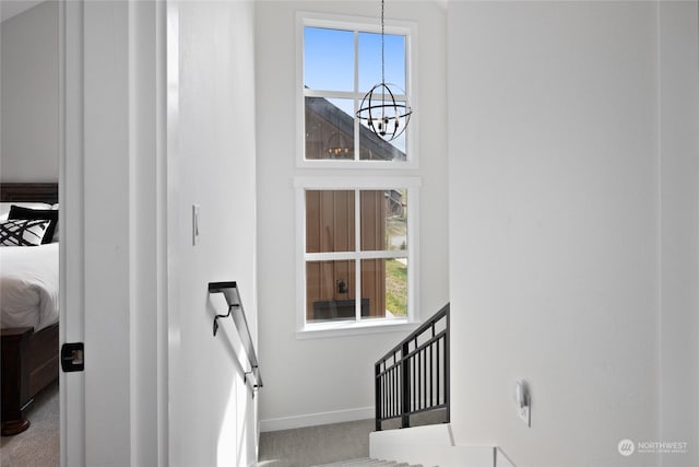 stairs featuring a notable chandelier, carpet floors, and a healthy amount of sunlight