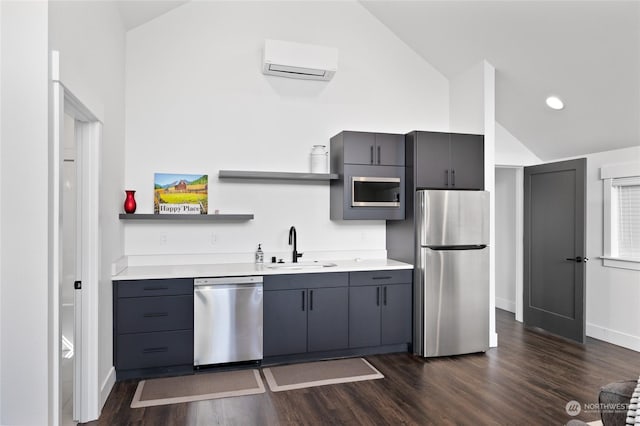 kitchen featuring vaulted ceiling, appliances with stainless steel finishes, an AC wall unit, sink, and dark hardwood / wood-style flooring