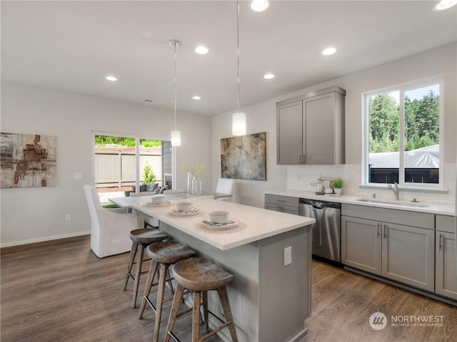 kitchen featuring dishwasher, gray cabinetry, sink, pendant lighting, and dark hardwood / wood-style floors