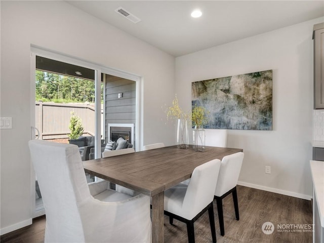 dining area with dark hardwood / wood-style floors and a fireplace