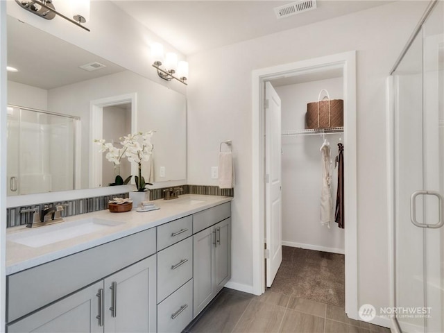 bathroom featuring a shower with shower door and vanity