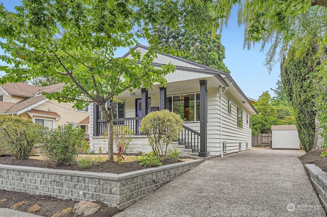 bungalow featuring a garage, an outbuilding, and covered porch