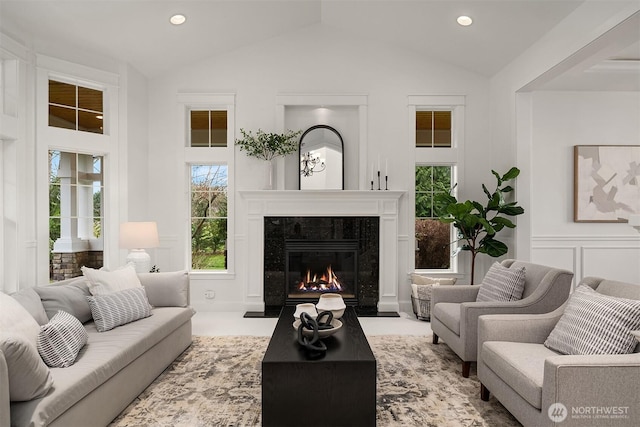 living room with a decorative wall, recessed lighting, lofted ceiling, and a premium fireplace