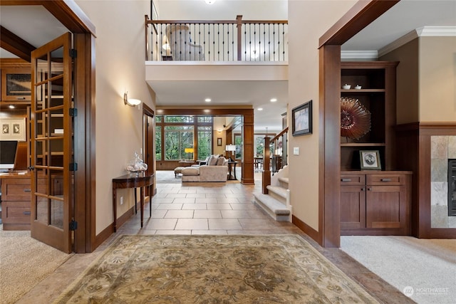 carpeted foyer entrance with a fireplace and ornamental molding