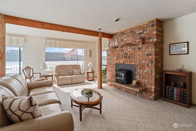 living room featuring carpet flooring, a water view, beam ceiling, a wood stove, and a textured ceiling