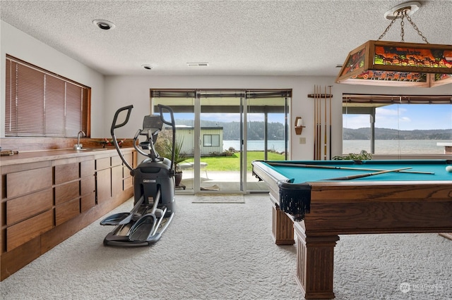 rec room with a water and mountain view, sink, light colored carpet, billiards, and a textured ceiling