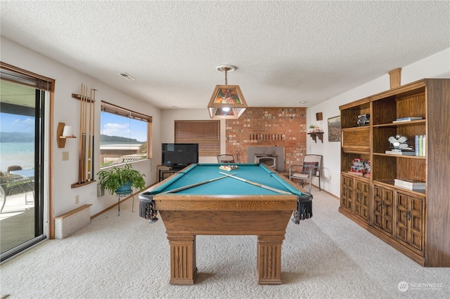 game room with a textured ceiling, billiards, a brick fireplace, light carpet, and a water view