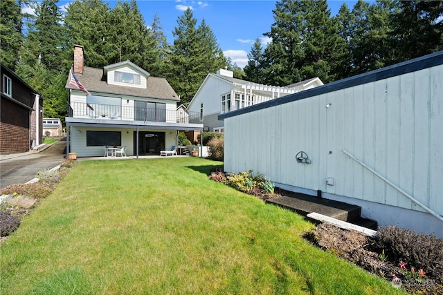 back of house with a deck, a lawn, and a patio