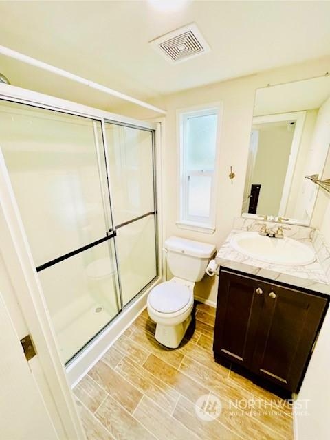 bathroom featuring an enclosed shower, vanity, and toilet