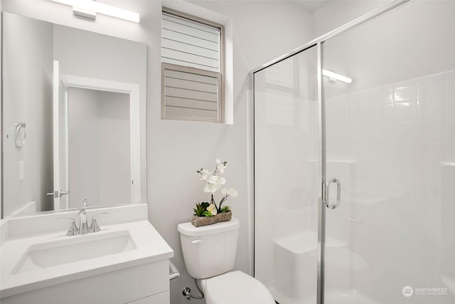 bathroom featuring a shower with door, toilet, and vanity