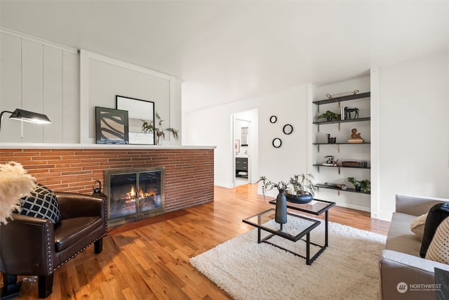 living room featuring a brick fireplace and wood-type flooring