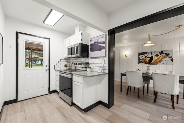 kitchen featuring hanging light fixtures, decorative backsplash, white cabinets, and appliances with stainless steel finishes