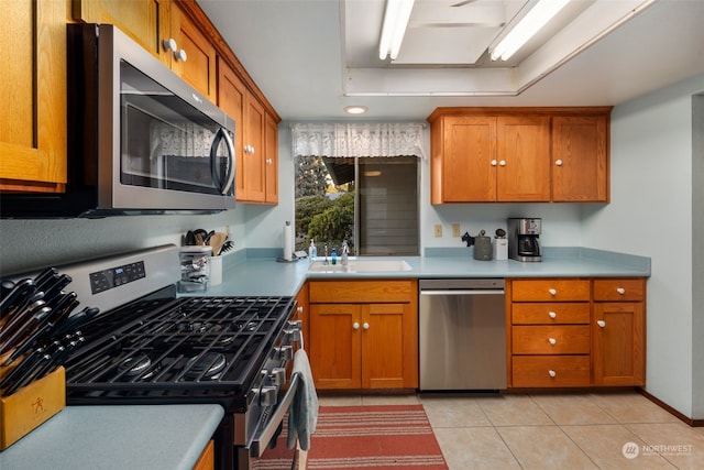 kitchen featuring stainless steel appliances, a tray ceiling, sink, and light tile patterned floors