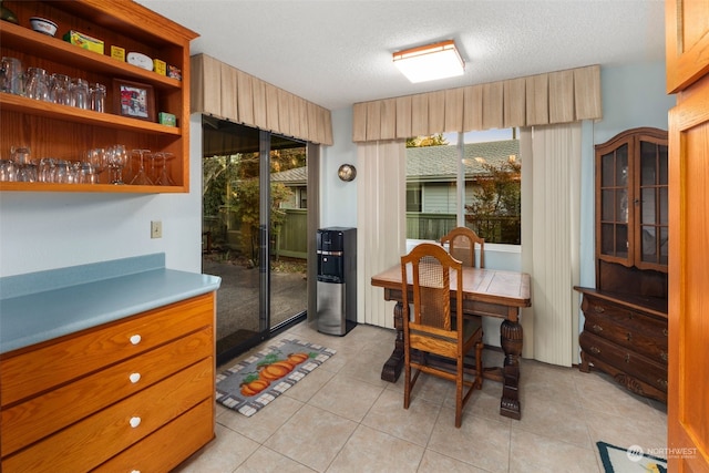 tiled dining area featuring a healthy amount of sunlight and a textured ceiling