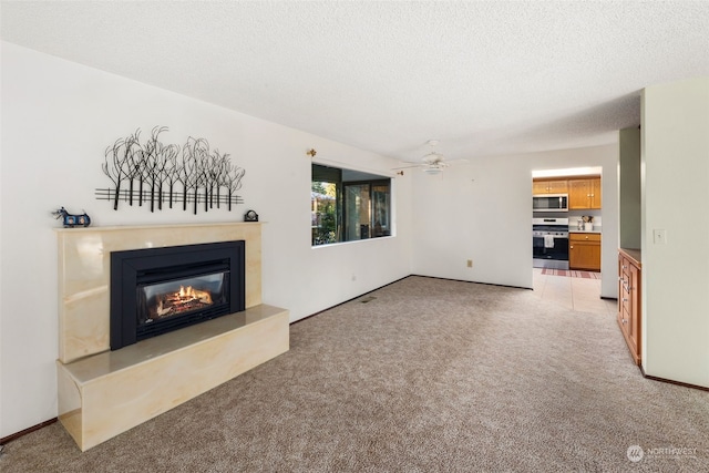 unfurnished living room featuring ceiling fan, light colored carpet, and a textured ceiling