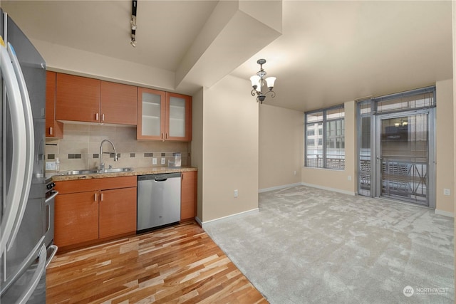 kitchen featuring appliances with stainless steel finishes, a chandelier, light carpet, sink, and backsplash