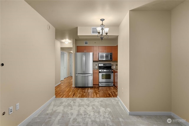 kitchen featuring pendant lighting, light colored carpet, an inviting chandelier, and appliances with stainless steel finishes