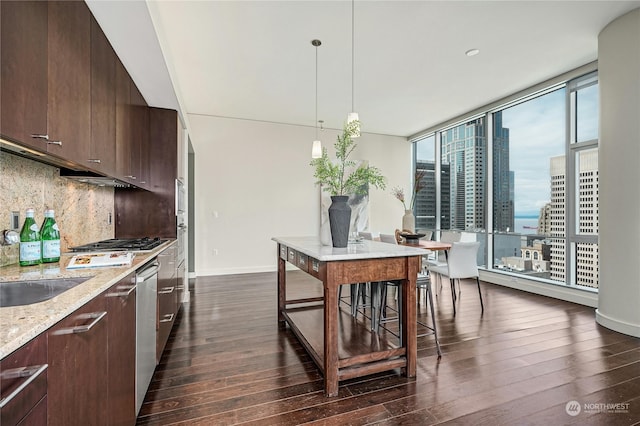 kitchen with decorative light fixtures, decorative backsplash, dark brown cabinets, and a healthy amount of sunlight