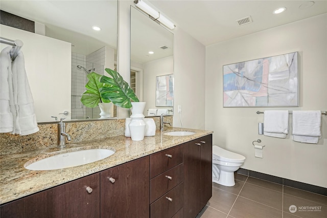 bathroom with vanity, toilet, tile patterned floors, and tiled shower