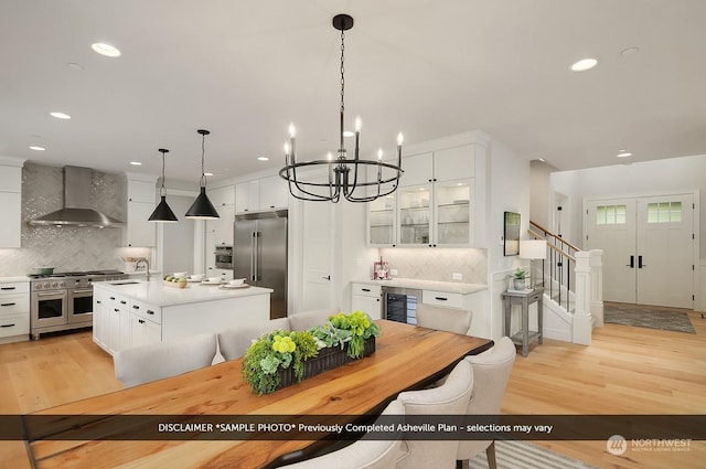 kitchen with wall chimney exhaust hood, a center island with sink, high quality appliances, and tasteful backsplash