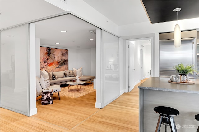 interior space featuring decorative light fixtures, hardwood / wood-style flooring, and stainless steel built in fridge