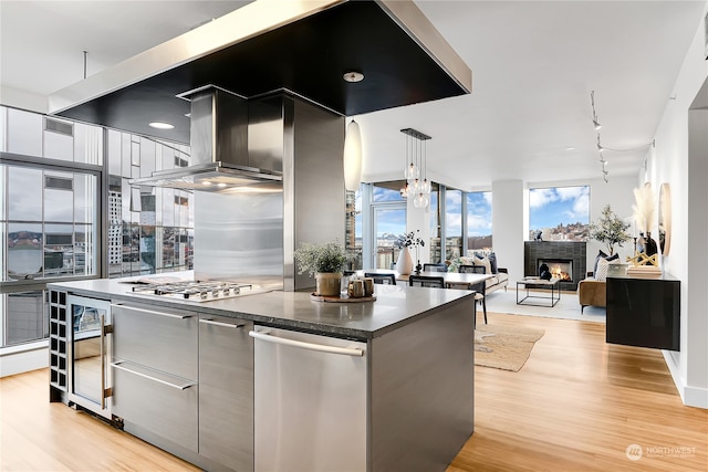 kitchen featuring hanging light fixtures, light hardwood / wood-style flooring, stainless steel gas cooktop, and island exhaust hood