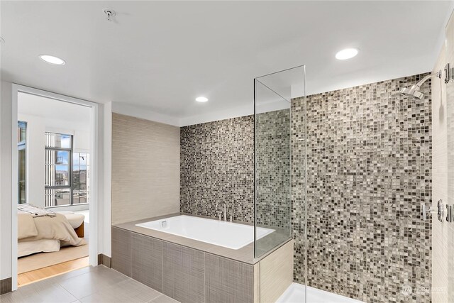 bathroom featuring independent shower and bath, tile patterned flooring, and tile walls