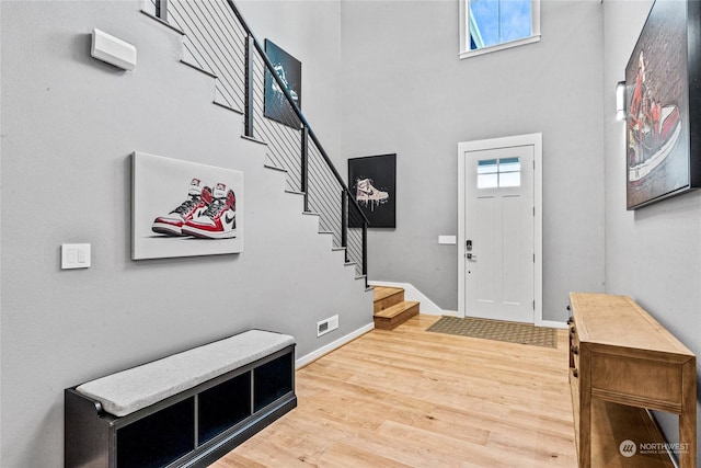 entrance foyer with a towering ceiling, wood-type flooring, and plenty of natural light