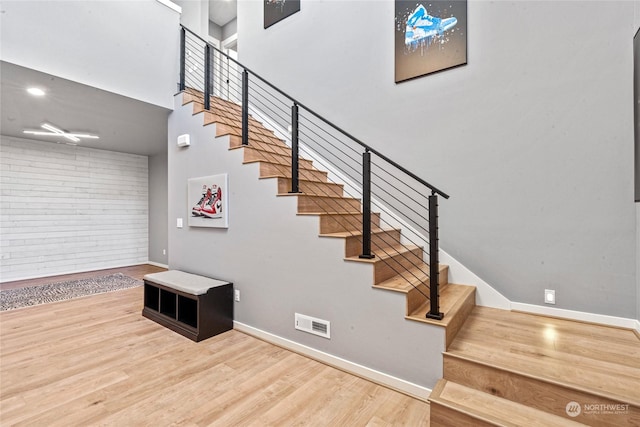 stairway with hardwood / wood-style flooring and a towering ceiling