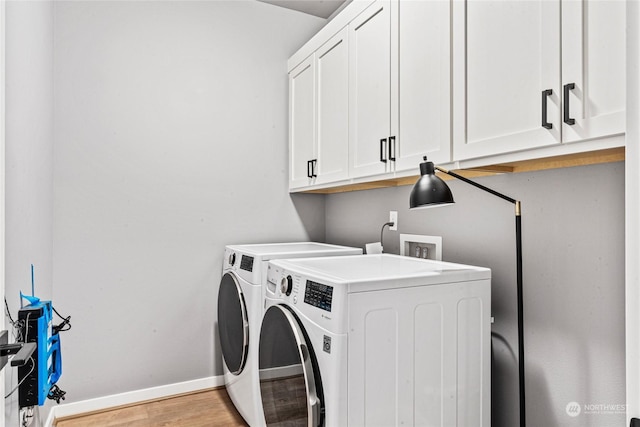 laundry room featuring light hardwood / wood-style floors, cabinets, and washing machine and clothes dryer