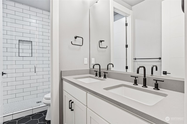 bathroom with vanity, tile patterned flooring, toilet, and tiled shower