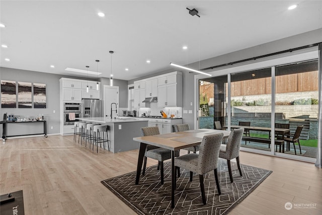 dining area with sink and light wood-type flooring