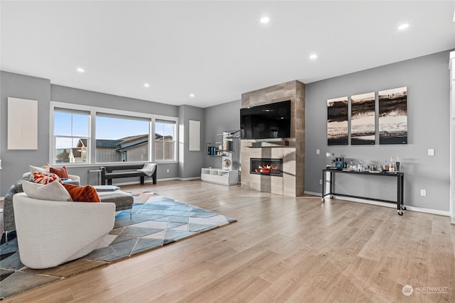 living room featuring a tiled fireplace and light hardwood / wood-style flooring