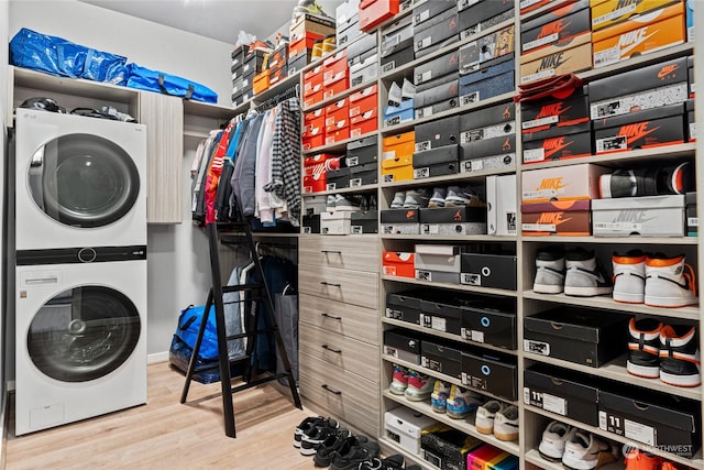 laundry room with stacked washer and clothes dryer and hardwood / wood-style floors