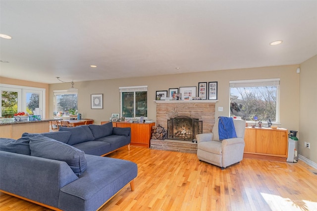 living room with a stone fireplace and light hardwood / wood-style flooring