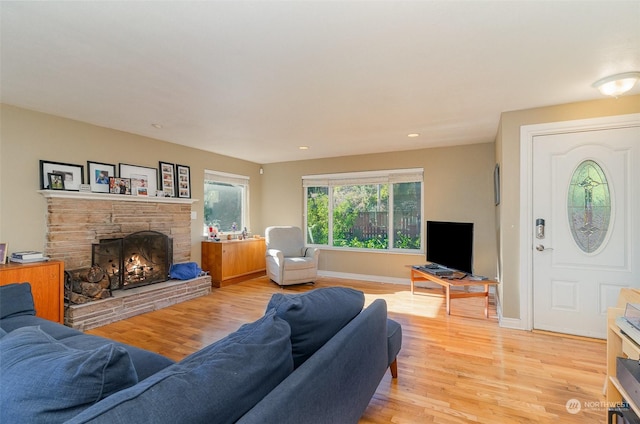 living room featuring a stone fireplace and light hardwood / wood-style floors