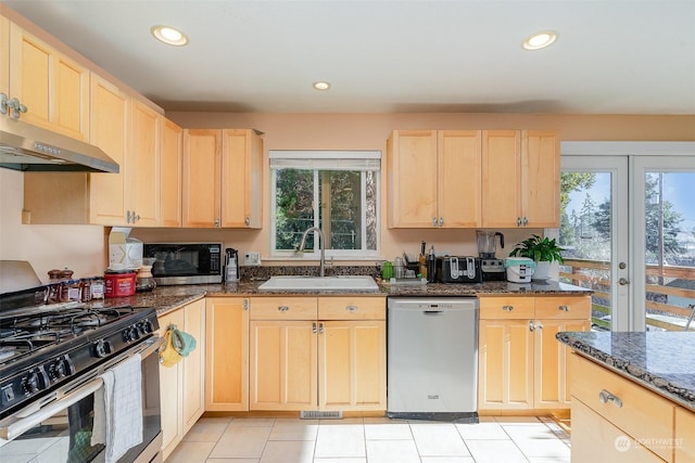 kitchen featuring appliances with stainless steel finishes, sink, light brown cabinets, and dark stone counters