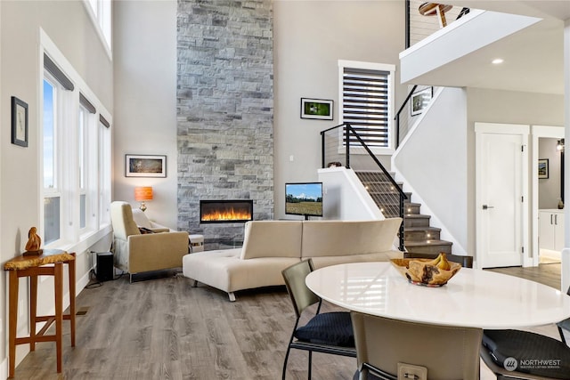 living room with light hardwood / wood-style flooring, a towering ceiling, and a fireplace