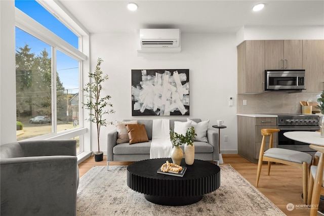 living room featuring a healthy amount of sunlight, a wall mounted air conditioner, and light wood-type flooring