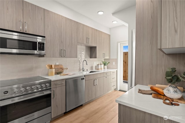 kitchen featuring appliances with stainless steel finishes, light brown cabinetry, sink, and light wood-type flooring