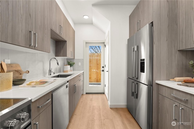 kitchen featuring sink, backsplash, stainless steel appliances, and light hardwood / wood-style floors