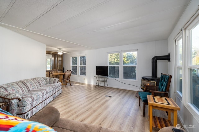 living room featuring a textured ceiling, light hardwood / wood-style flooring, a healthy amount of sunlight, and a wood stove