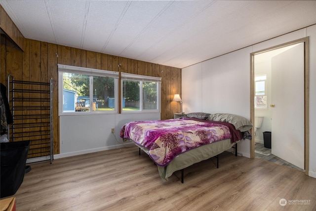 bedroom featuring wood walls, a textured ceiling, and light hardwood / wood-style flooring