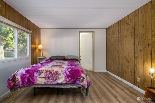 bedroom with light wood-type flooring and wooden walls