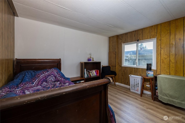 bedroom with light hardwood / wood-style flooring and wood walls